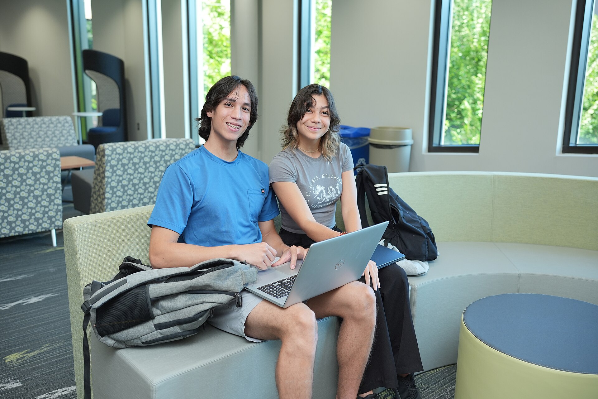 Two students smiling with a laptop